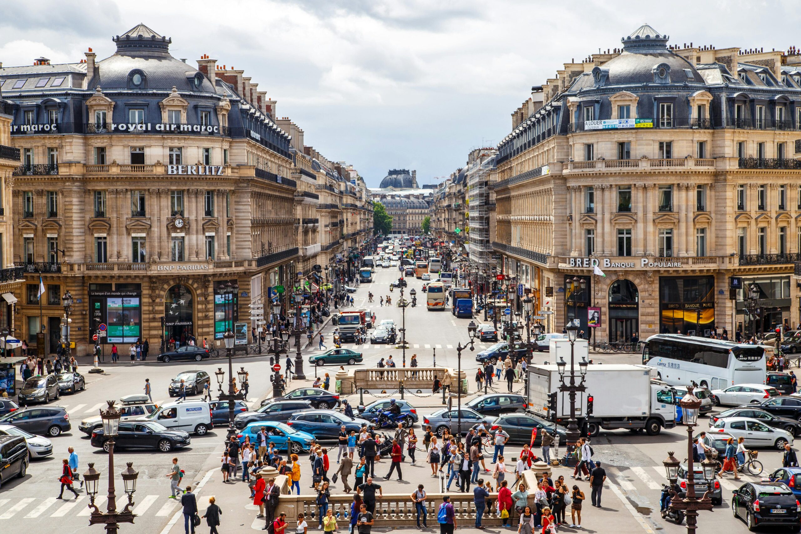 Vibrant street view of central Paris filled with people and traffic on a summer day.