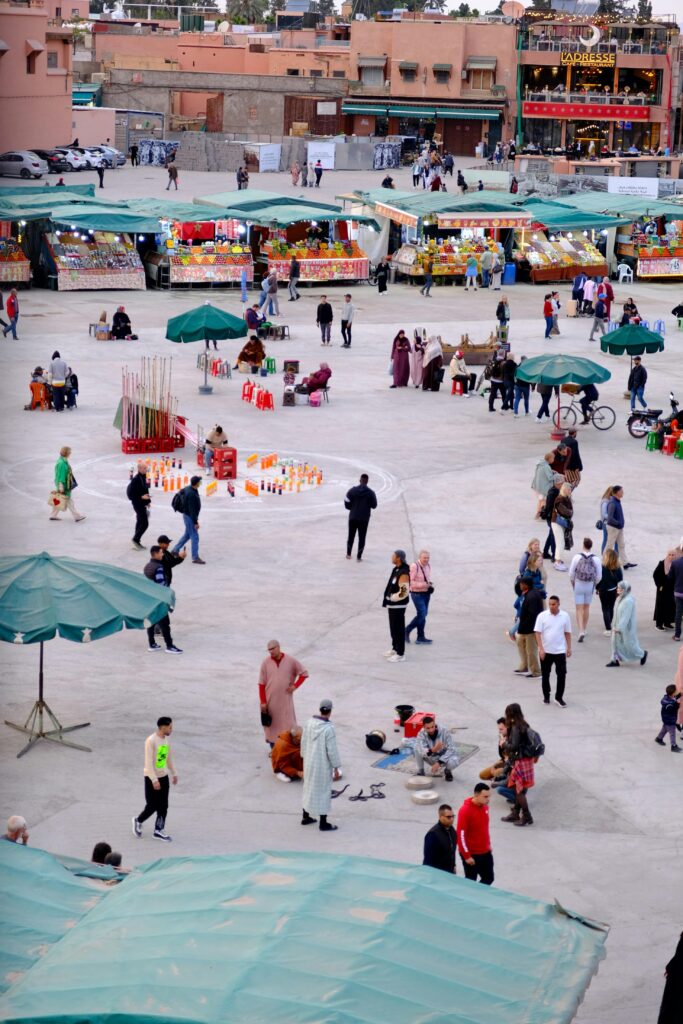 A bustling outdoor market in Marrakech with vendors and visitors showcasing vibrant local culture.