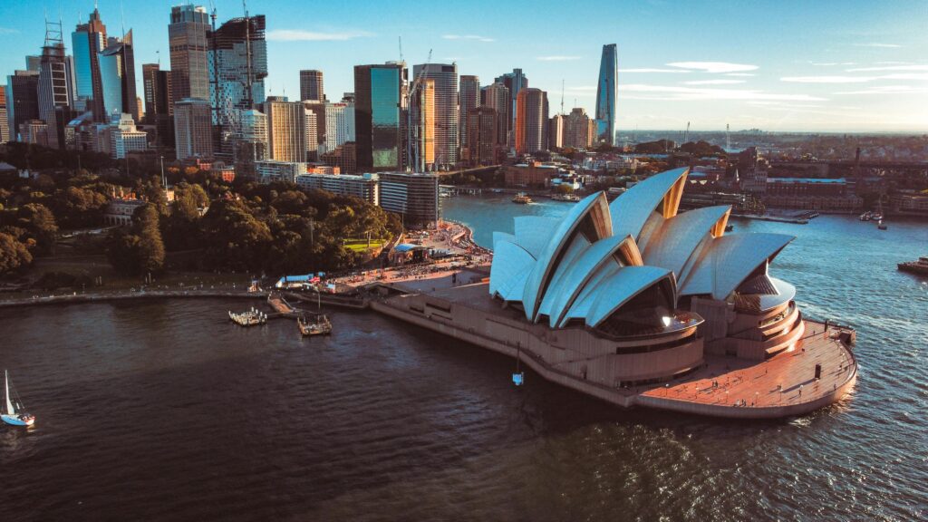 Aerial view of Sydney Opera House with city skyline at sunset, Australia.